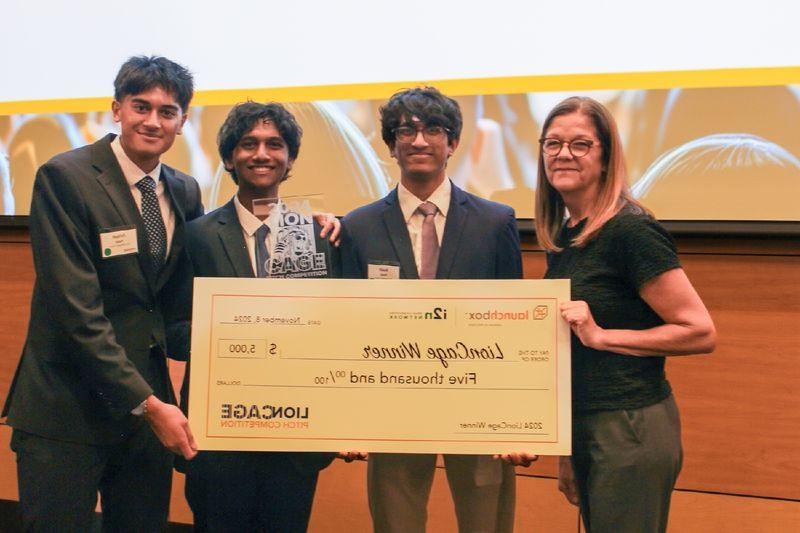 three men and a woman holding a large check